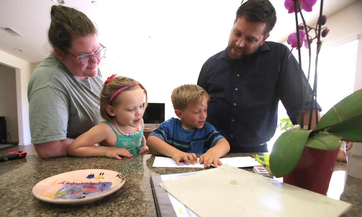 Couple Steven and Katherine Wolf with their daughter Rebekah, 4, look over Everett's, 6, reading project.