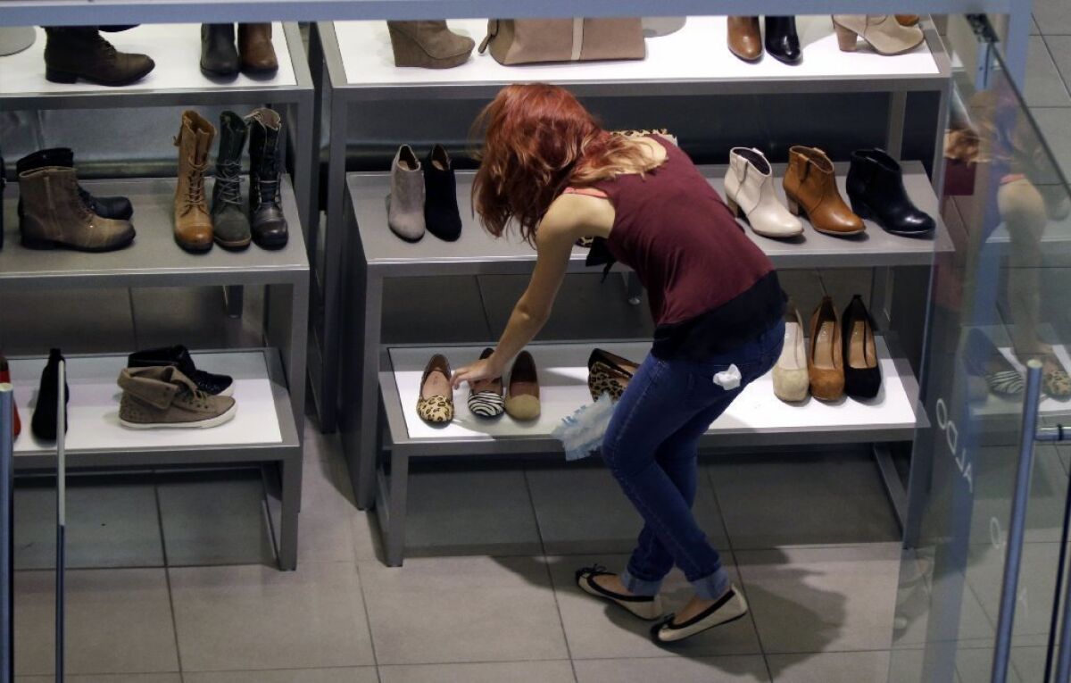 A clerk straightens shoe displays in Salem, N.H. Americans increased their spending in September at twice the rate that their income grew, a sign of confidence in the economy.