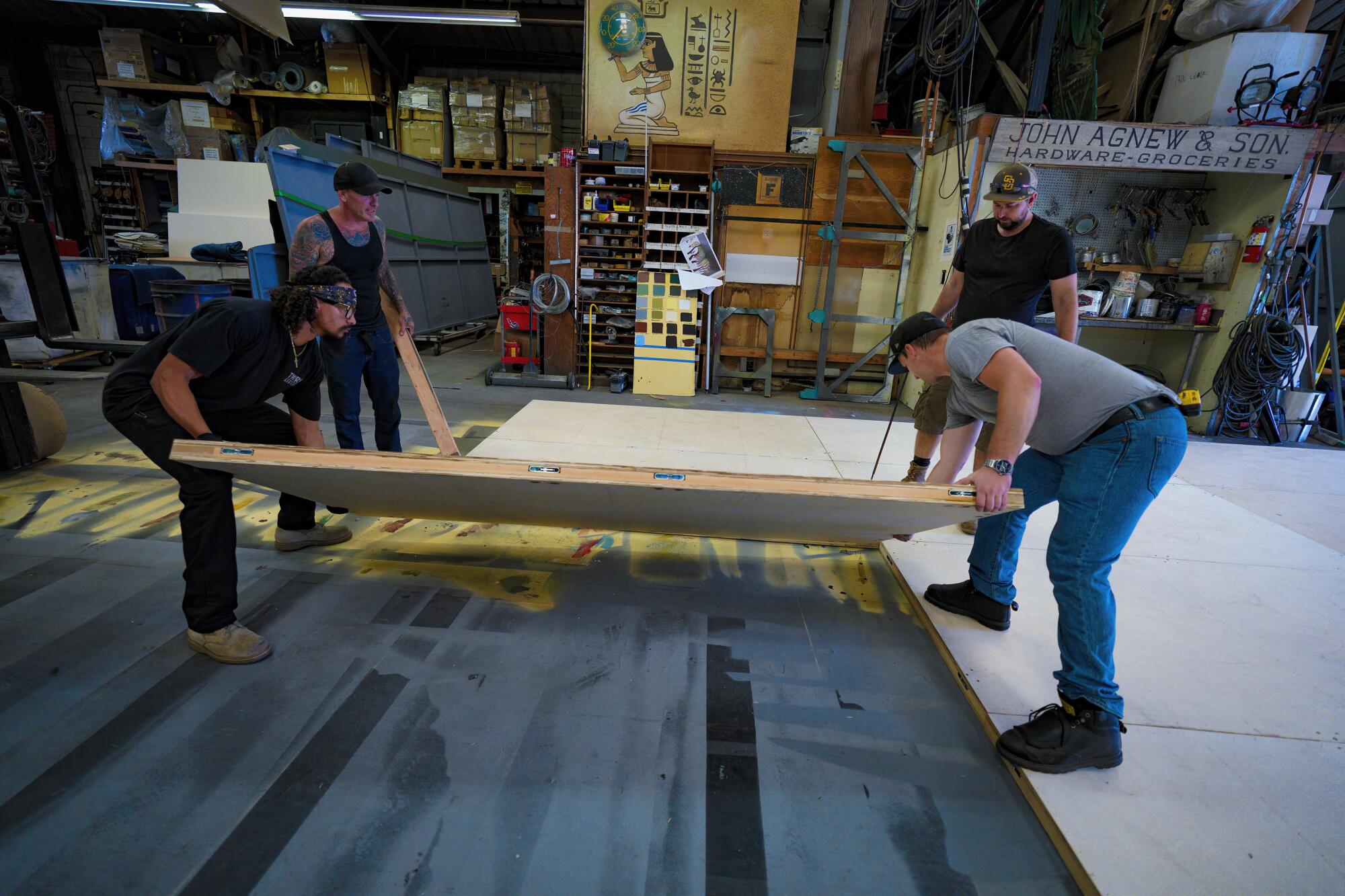 Workers at the San Diego Opera Scenic Studio assemble a large temporary flooring.