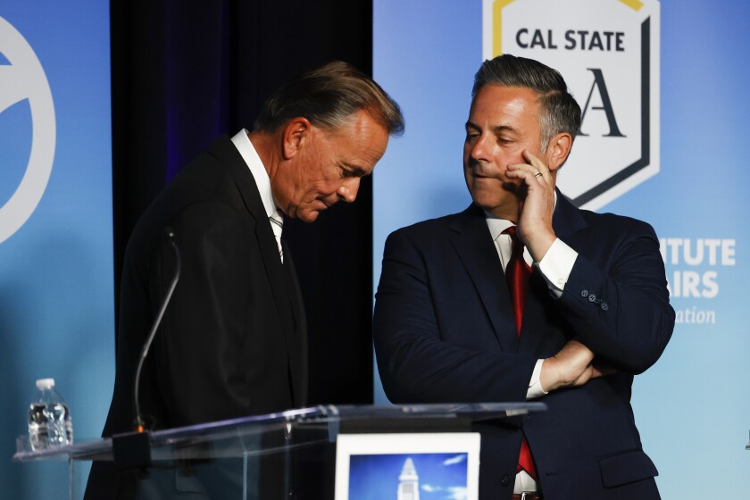 Rick Caruso, left, speaks with Joe Buscaino at the start of Sunday's mayoral debate at Cal State L.A.