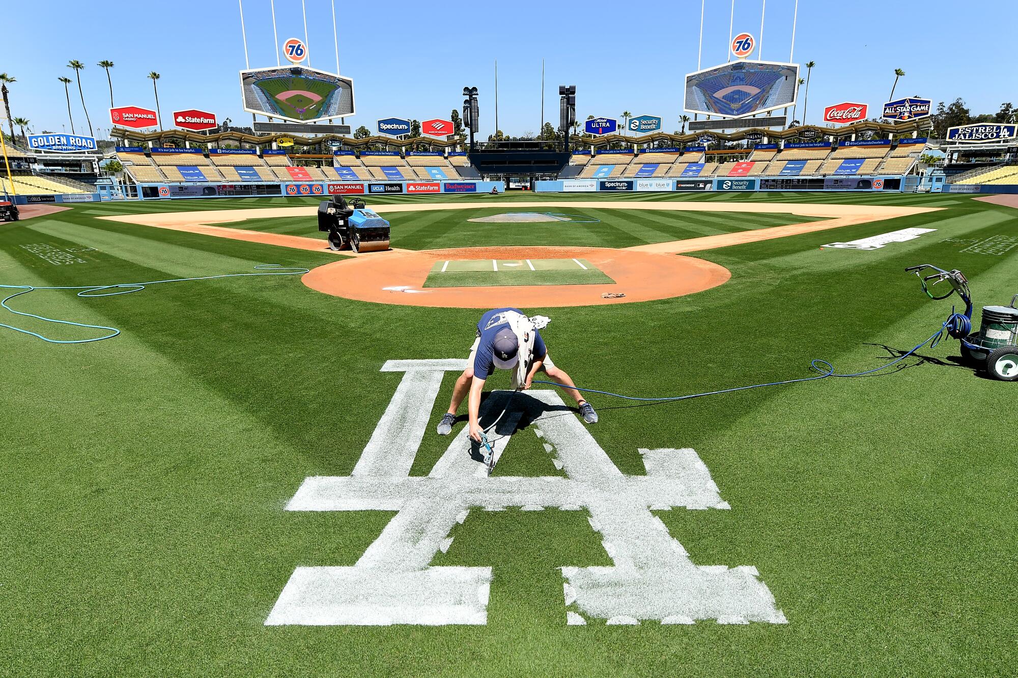 Dodgers ground crew member Justin Patenaude paints the field in preparation for opening day Friday. 