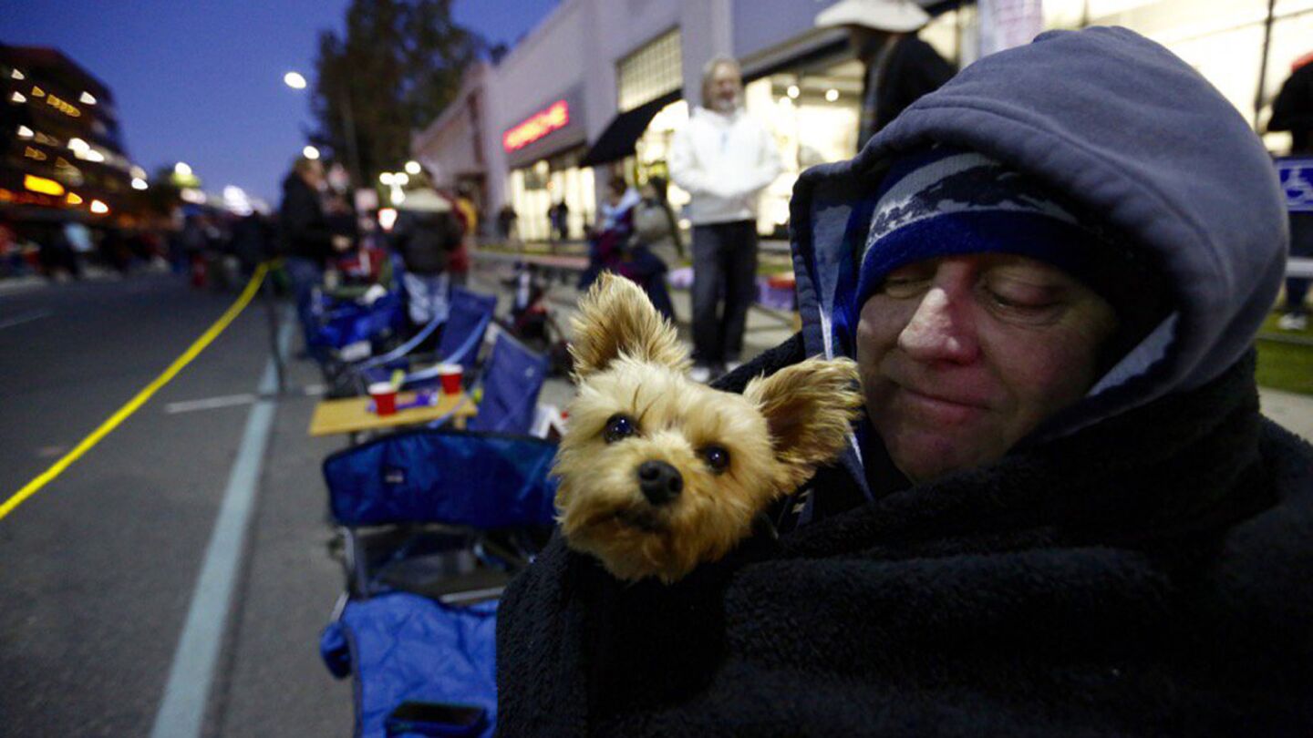 Tom Brock from San Francisco and his dog Gino keep each other warm on the Rose Parade route.