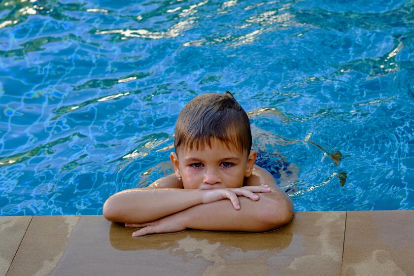 Nice boy at edge of pool, wet hair, reddened eyes from water