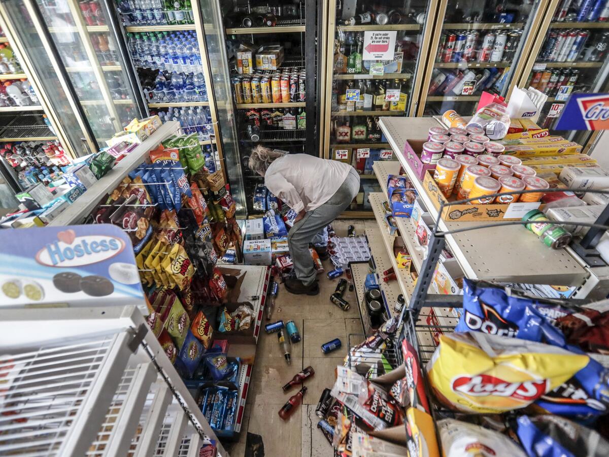 A customer rummages through the rubble at the severely damaged Shell food mart in Trona, Calif., less than a day after the Ridgecrest earthquake in July.