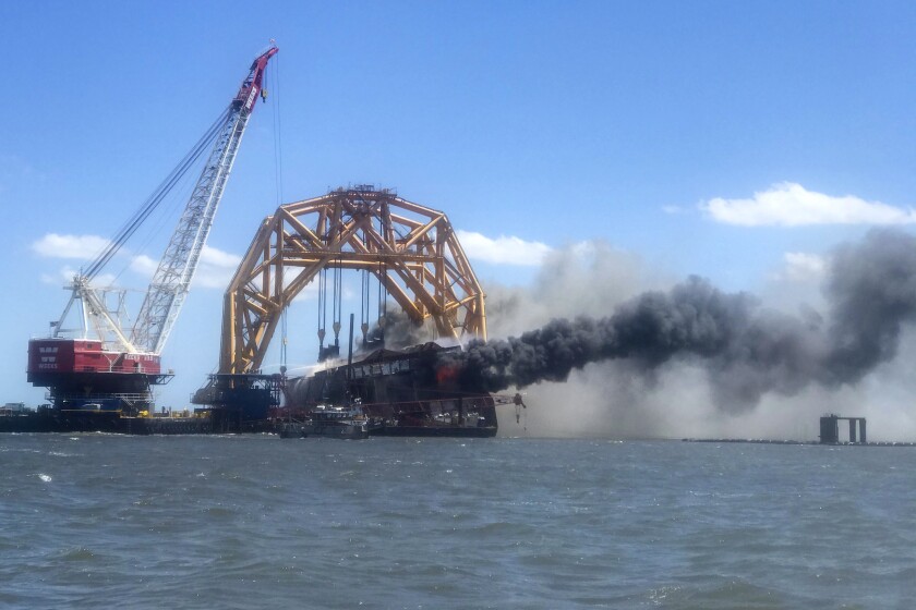 In this photo provided by the Altamaha Riverkeeper, smoke pours from the remnants of the capsized cargo ship Golden Ray on Friday, May 14, 2021, off St. Simons Island, Ga. Crews have spent months dismantling the ship in gigantic chunks after it overturned in September 2019. (Susan Inman/Altamaha Riverkeeper via AP)