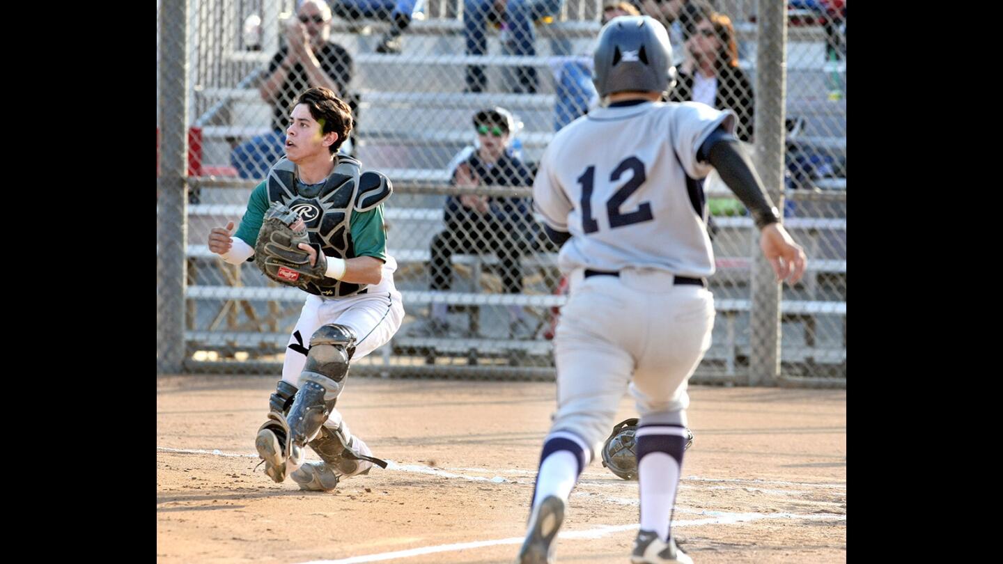 Providence catcher Alec Saavedra looks for the throw as Flintridge Prep's Andrew Tsangeos makes the first home run during a game on Tuesday, May 24, 2016.