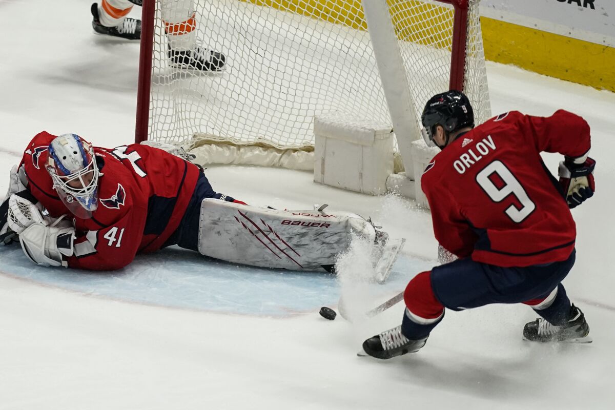 Washington Capitals defenseman Dmitry Orlov (9) clears the puck from in front of goaltender Vitek Vanecek (41) during the first period of an NHL hockey game against the Philadelphia Flyers, Friday, May 7, 2021, in Washington. (AP Photo/Alex Brandon)