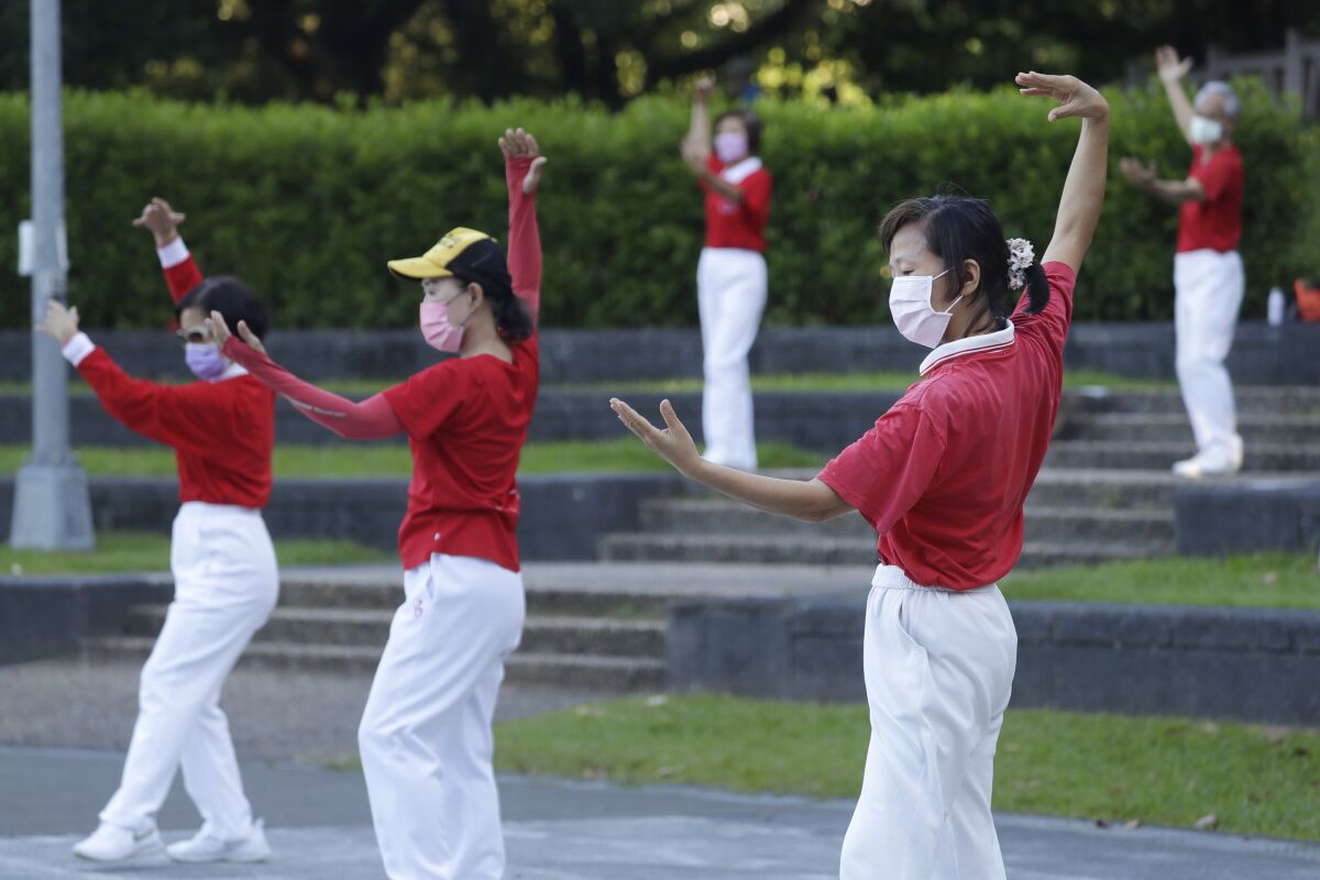 People wearing face masks to protect against the spread of the coronavirus take morning exercises at a park in Taipei, Taiwan, Wednesday, Sept. 28, 2022. (AP Photo/Chiang Ying-ying)