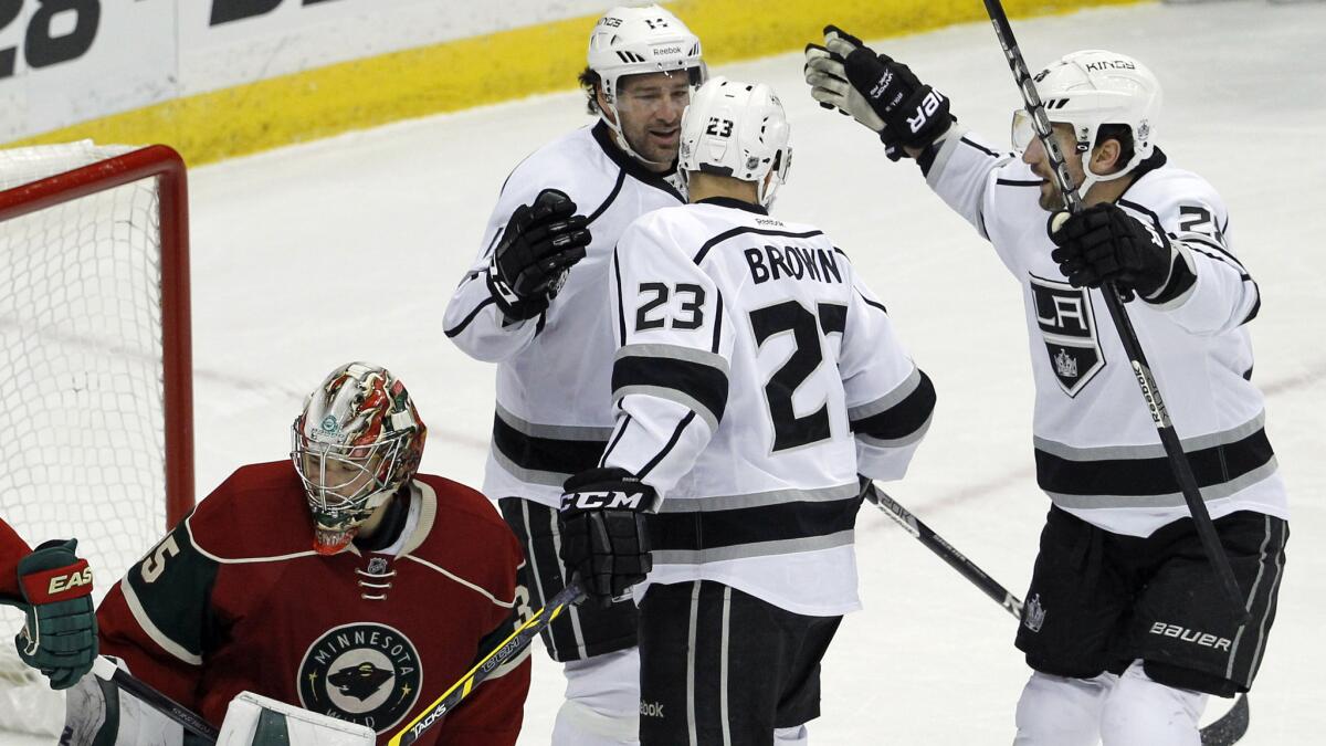 Kings captain Dustin Brown, center, is congratulated by teammates Justin Williams, second left, and Jarret Stoll, right, after scoring a goal on Minnesota goalie Darcy Kuemper during the Kings' 4-0 win Wednesday.