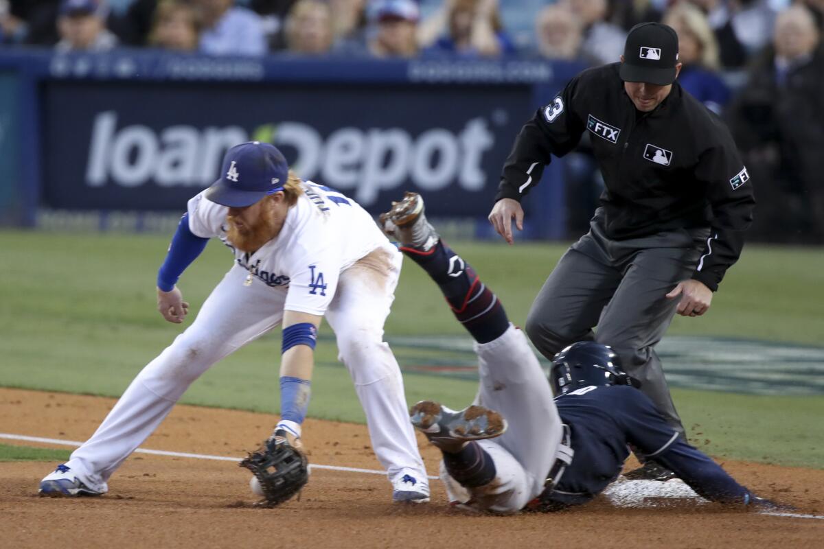 Atlanta's Eddie Rosario dives into third base and beats the tag of Dodgers third baseman Justin Turner.