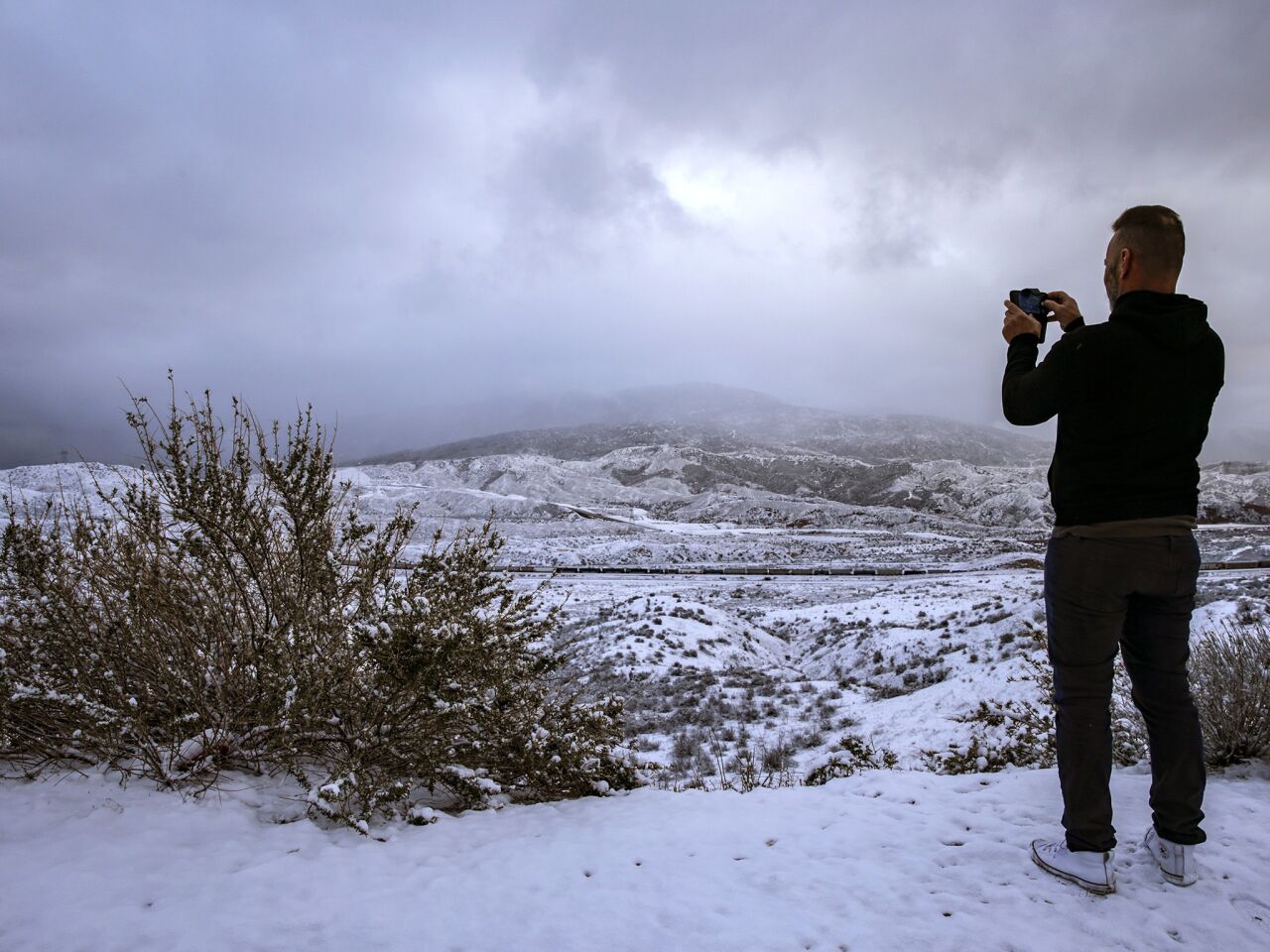 Greg Hunkle, on his way to Las Vegas, stops at Cajon Summit on Thursday morning to take a photo of snow-covered mountains.