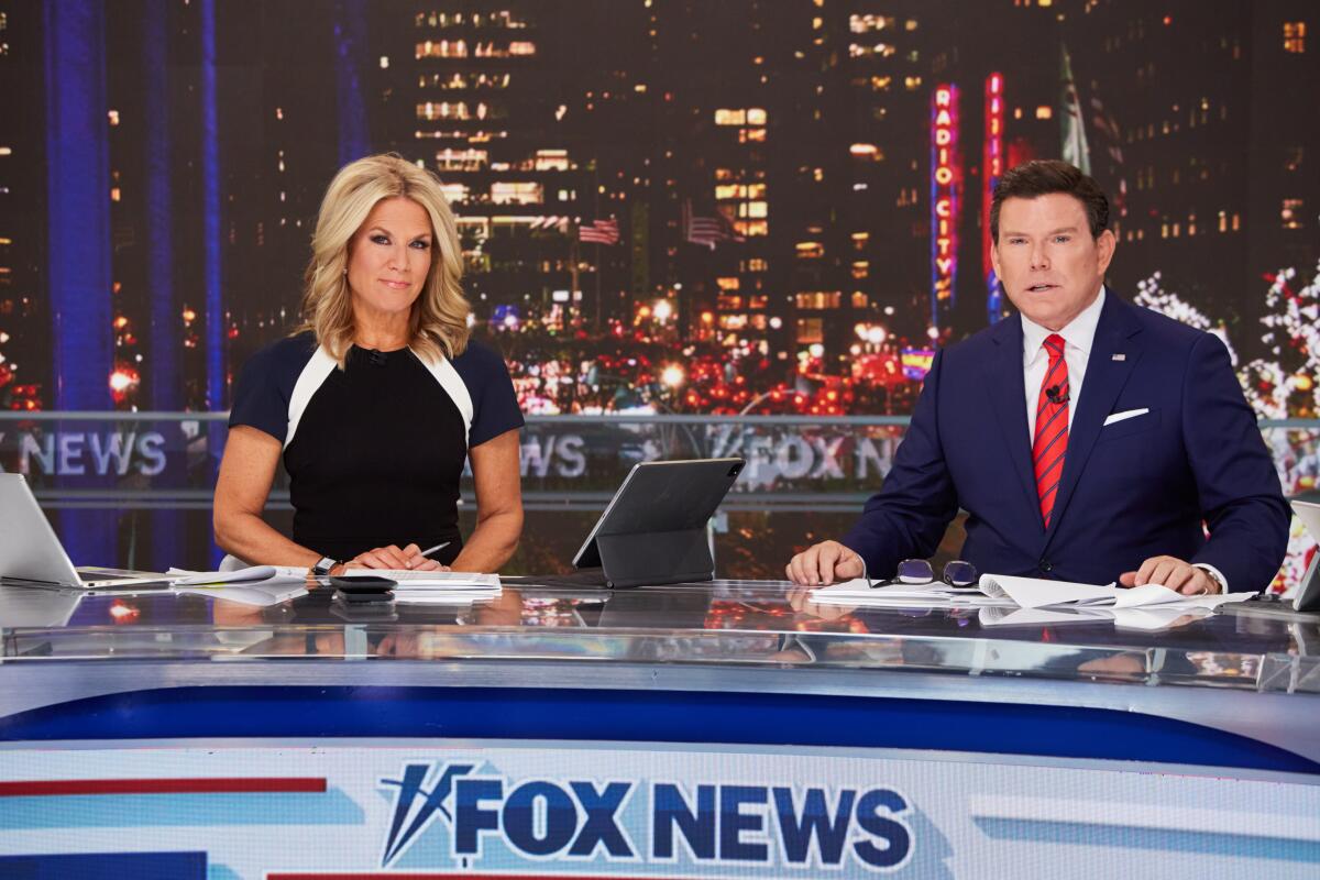 A woman and a man sit at a Fox News anchor desk.