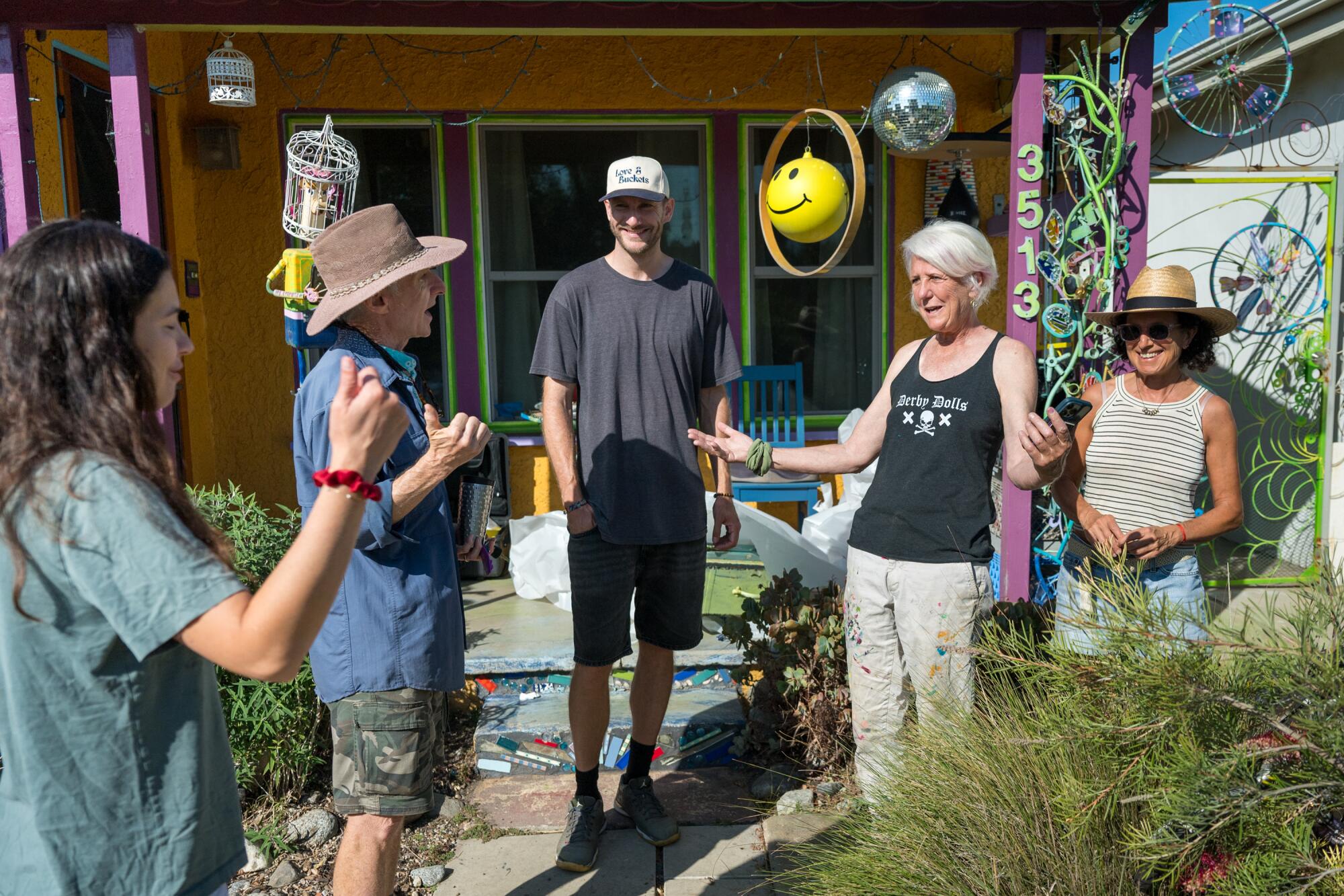 Five people stand in front of a house.