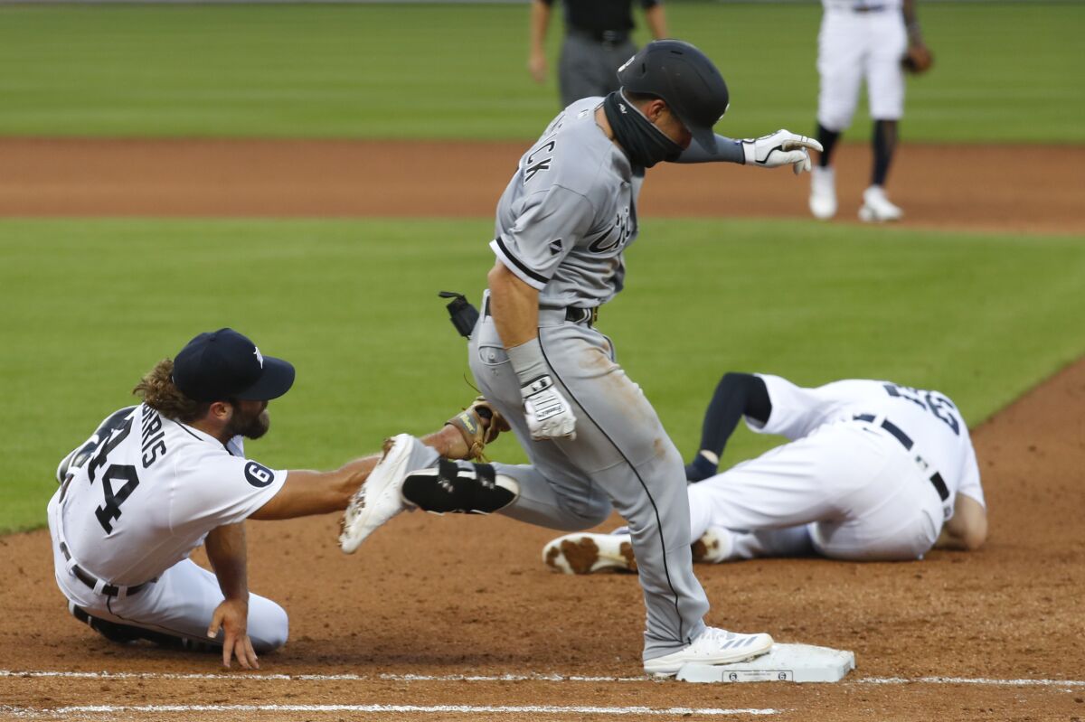 Detroit Tigers pitcher Daniel Norris, left, dives to tag out Chicago White Sox's Danny Mendick, center, as first baseman C.J. Cron (26) lies injured on the field in the fourth inning of a baseball game in Detroit, Monday, Aug. 10, 2020. (AP Photo/Paul Sancya)