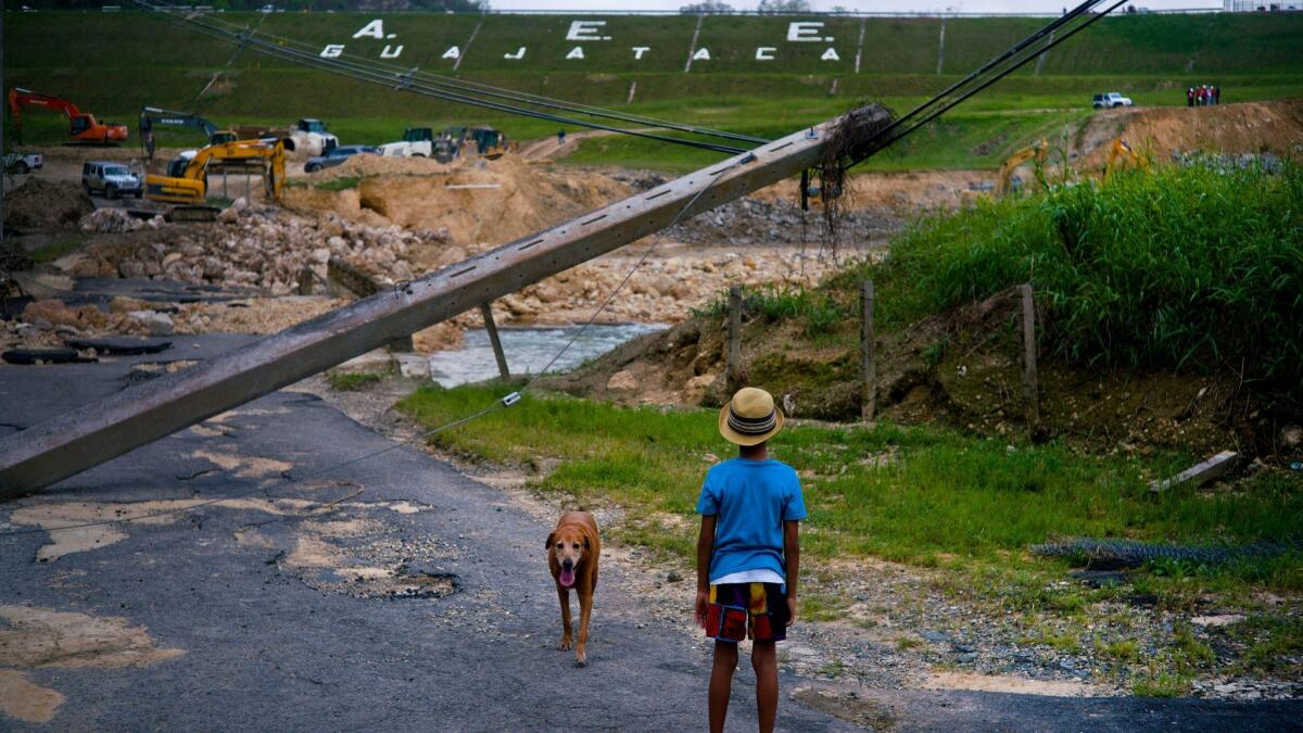 A boy watches the repairs of Guajataca Dam, which cracked during Hurricane Maria, in Quebradillas, Puerto Rico. Experts said the island could face nearly two decades of further economic stagnation and a steep drop in population as a result of Maria.