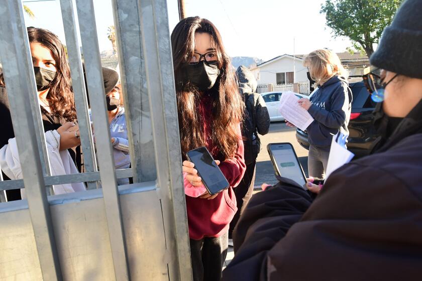 A students shows her negative Covid-test result from her cellphone for entry to Olive Vista Middle School on the first day back following the winter break amid a dramatic surge in Covid-19 cases across Los Angeles County on January 11, 2022 in Sylmar, California. - Tens of thousands of Los Angeles Unified School District students returned to classes today after the winter break with district requirements for all staff and students to be tested for Covid-19 from the thousands of take-home test kits provided to students with a negative result allowing entry. (Photo by Frederic J. BROWN / AFP) (Photo by FREDERIC J. BROWN/AFP via Getty Images)