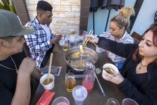 ARCADIA, CA - March 06: Diners from left: Jacob Vargas, Desmond Thompson, Mia Sheen, Samantha Sharp eat hot pot Sichuan style dining at Hai Di Lao Hot Pot restaurant at the Westfield Santa Anita shopping complex Saturday, March 6, 2021 in Arcadia, CA. The complex has been offering "al fresco" dining since February and smaller groups have been eating together outdoors as a result of COVID-19 guidelines. The general story is how families and individuals have changed their hot pot eating habits due to COVID-19. Hot pot is traditionally a communal meal in which large families gather to celebrate the Lunar New Year or various other festivals and holidays. It's generally a cold-weather meal. It was very common for family groups of six to 12 (uncles, aunts, cousins, etc.) to eat together at Hai Di Lao. Now, you generally just see couples and small, nuclear families eating. (Allen J. Schaben / Los Angeles Times)