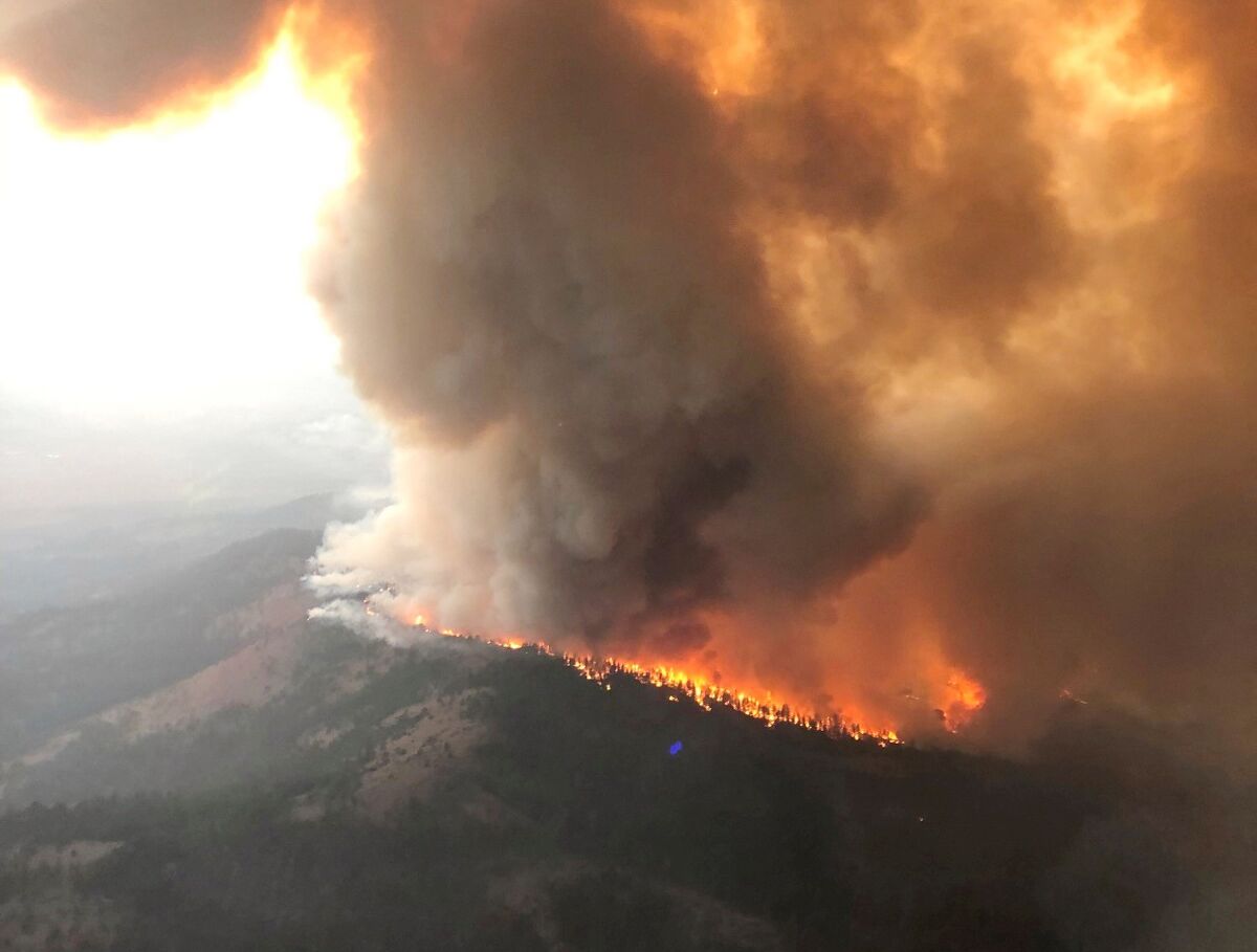 An aerial photo shows a huge plume of smoke on a ridge as the Dixie fire burns.