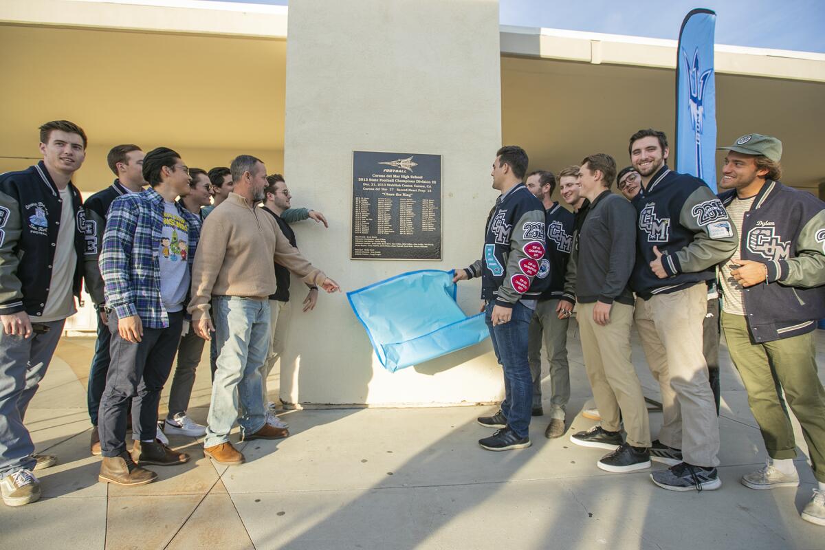 Members of the 2013 Corona del Mar football team unveil a plaque on campus Friday honoring the program's first CIF State title.