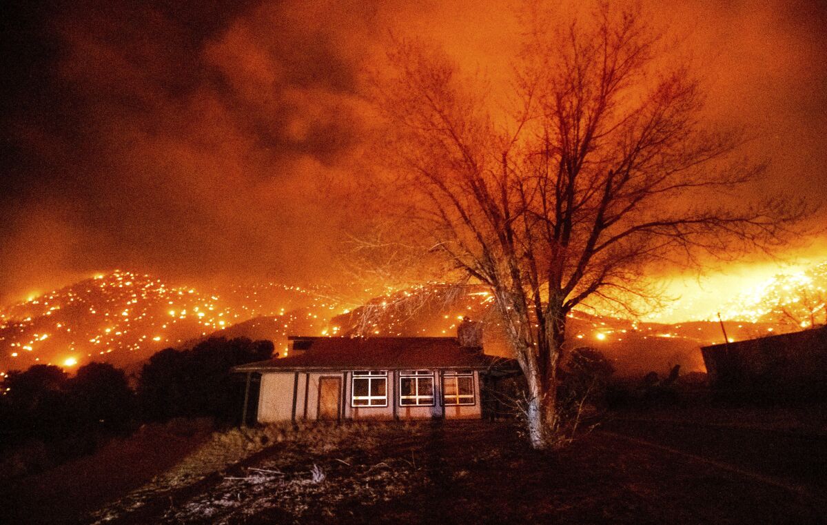 A home is surrounded by flames and embers in Mono County last year