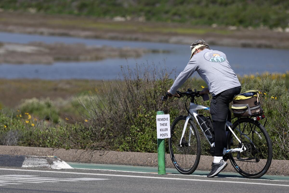 A cyclist stops to remove a sign on a pylon marking a 'protected' bike lane along South Coast Highway.
