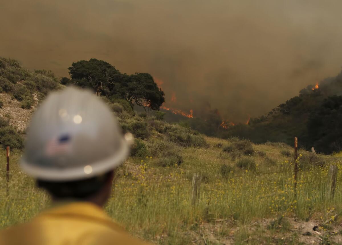 A firefighter watches the fast-moving Miguelito fire along San Miguelito Road on Tuesday.