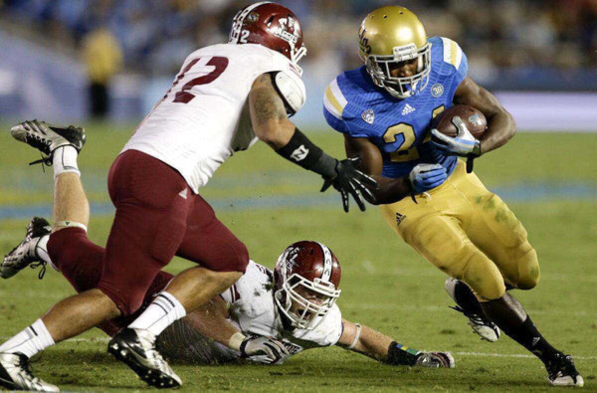 UCLA running back Paul Perkins gets past New Mexico State linebacker Bryan Bonilla as safety Tre Wilcoxen moves in for the tackle during a game earlier this season.