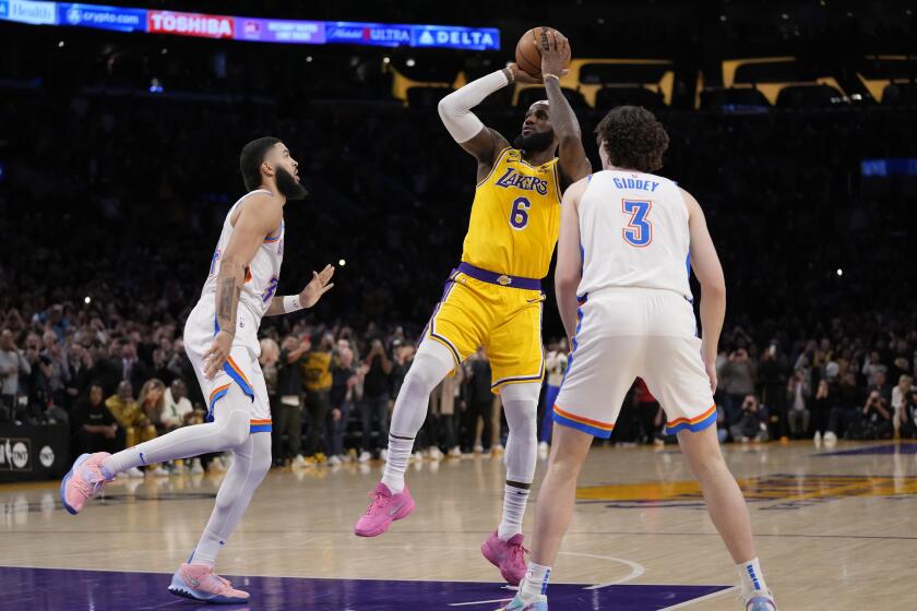 Los Angeles Lakers forward LeBron James, center, scores to pass Kareem Abdul-Jabbar to become the NBA's all-time leading scorer as Oklahoma City Thunder guard Josh Giddey, right, and forward Kenrich Williams defend during the second half of an NBA basketball game Tuesday, Feb. 7, 2023, in Los Angeles.(AP Photo/Ashley Landis)