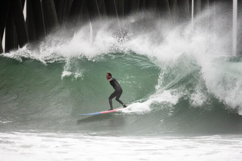 Amid light rain, Mike Watson of Huntington Beach rides a big wave in Huntington.