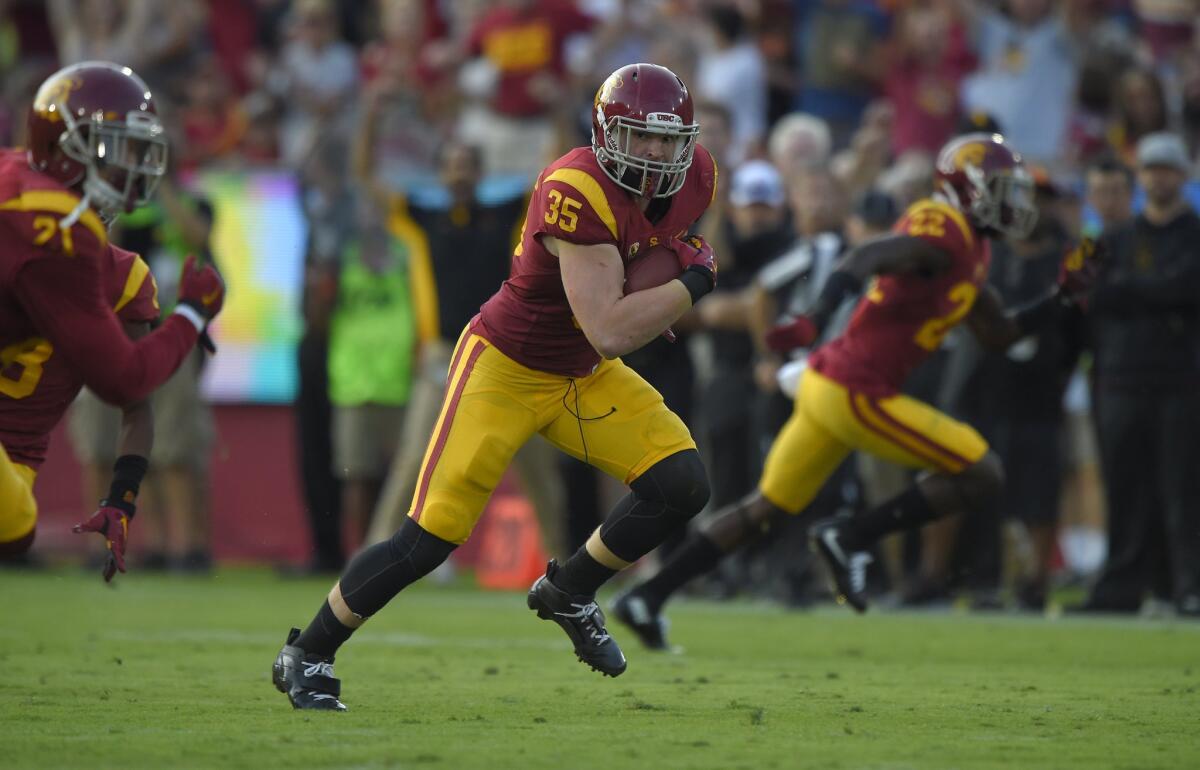 USC linebacker Cameron Smith runs with the ball after one of his three interceptions against Utah on Saturday at the Coliseum