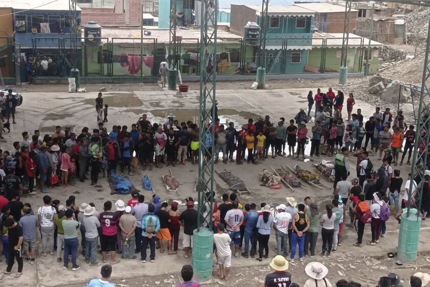 Residents stand around the bodies of persons who perished in recent landslides in Camana, Peru, Monday, Feb. 6, 2023. According to a preliminary report issued by Civil Defense, more than 30 people died as a consequence of non-stop heavy rains and landslides. (AP Photo/Ever Chambi)