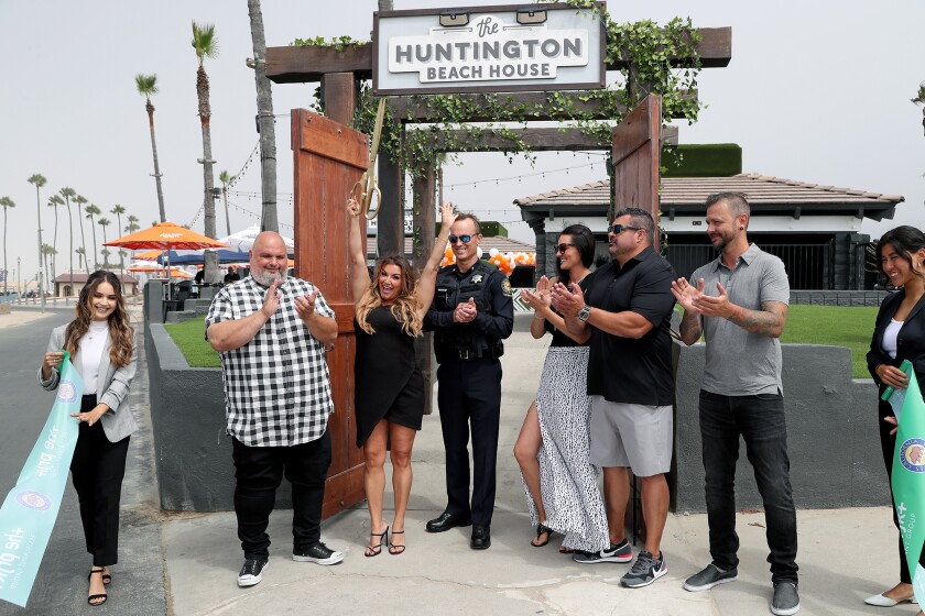 Prjkt chief executive Alicia Whitney raises the ceremonial scissors during a ceremony for the Huntington Beach House.