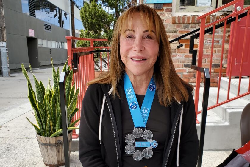 La Jolla resident Beverly Silldorf presents medals she won from completing major marathons across the world.