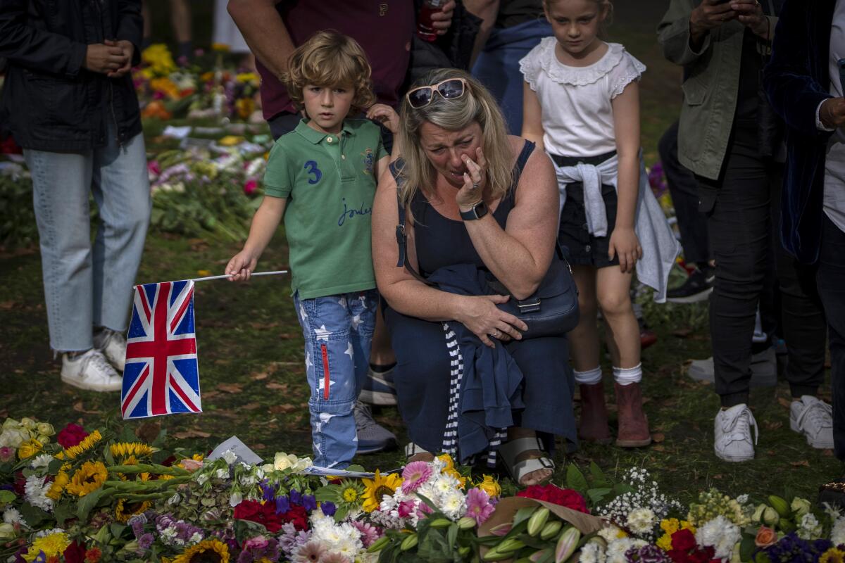 A woman cries next to flowers and messages for Queen Elizabeth II at the Green Park memorial, near Buckingham Palace, in London, Sept. 10, 2022. (AP Photo/Emilio Morenatti)