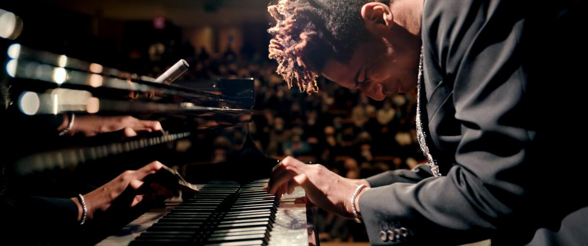 Jon Batiste hunches over his piano as he plays in "American Symphony."