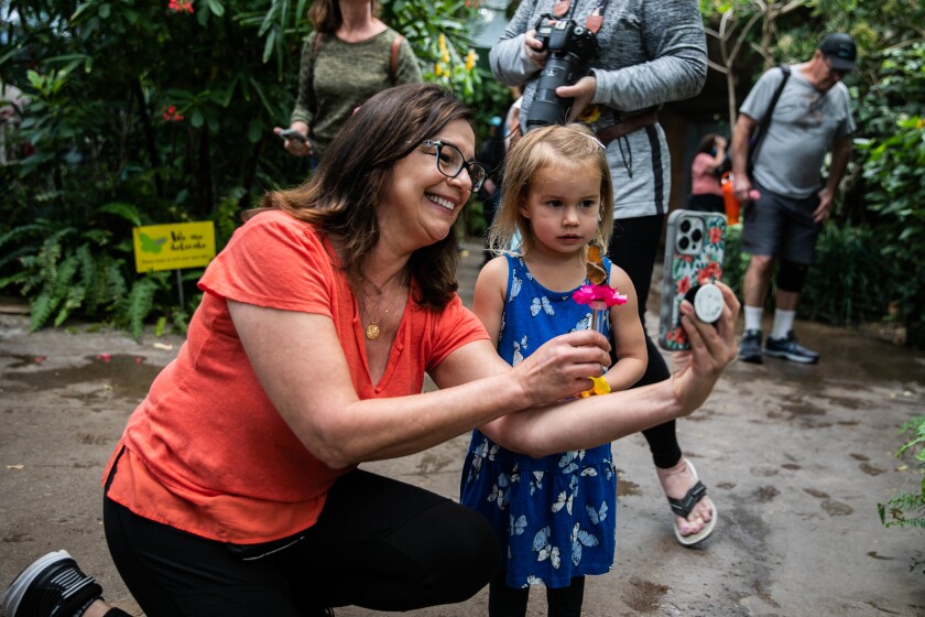 Debbie Berg y su nieta Mali Wade se toman una selfie mientras una mariposa come néctar en el Safari Park del zoológico de San Diego.