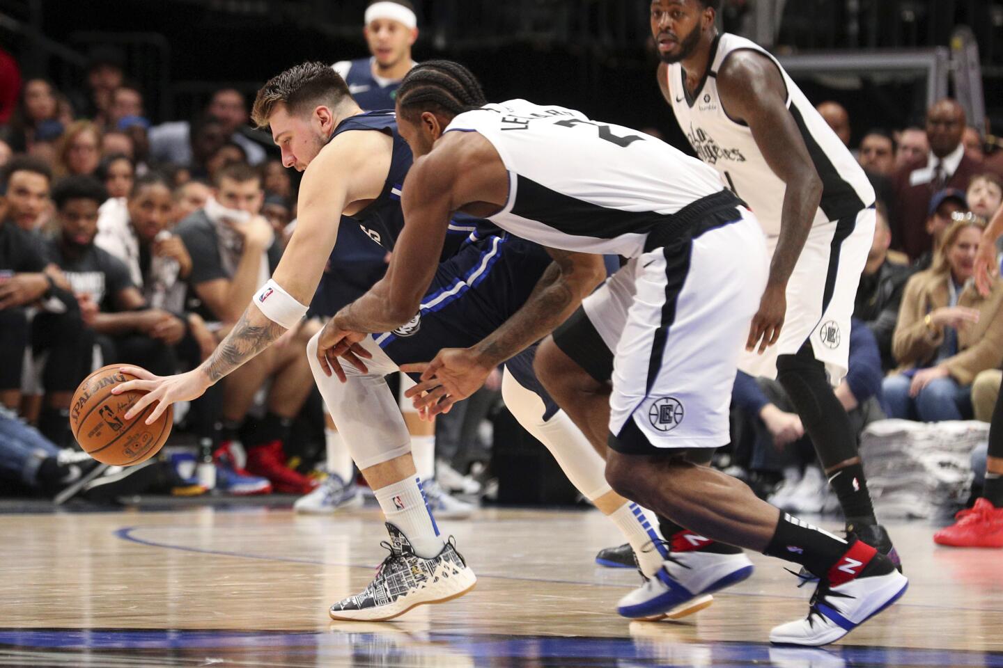 Luka Doncic and Kawhi Leonard chase a loose ball during the second half of a game Jan. 21.