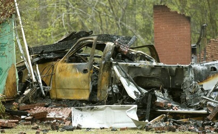 The remains of Kevin and Tammy Garner's home and a burnt vehicle are seen in Priceville, Ala. on Tuesday April 7, 2009. Authorities say a man suspected of shooting and killing his estranged wife and three others in rural north Alabama apparently took his own life as well. Travis Clemmons, chief investigator for the Lauderdale County sheriff's office, said the body of Kevin Garner was found Tuesday near his home in Priceville, which burned to the ground overnight. He said Garner apparently killed himself and a weapon was recovered. (AP Photo/The Decatur Daily, Brennen Smith)
