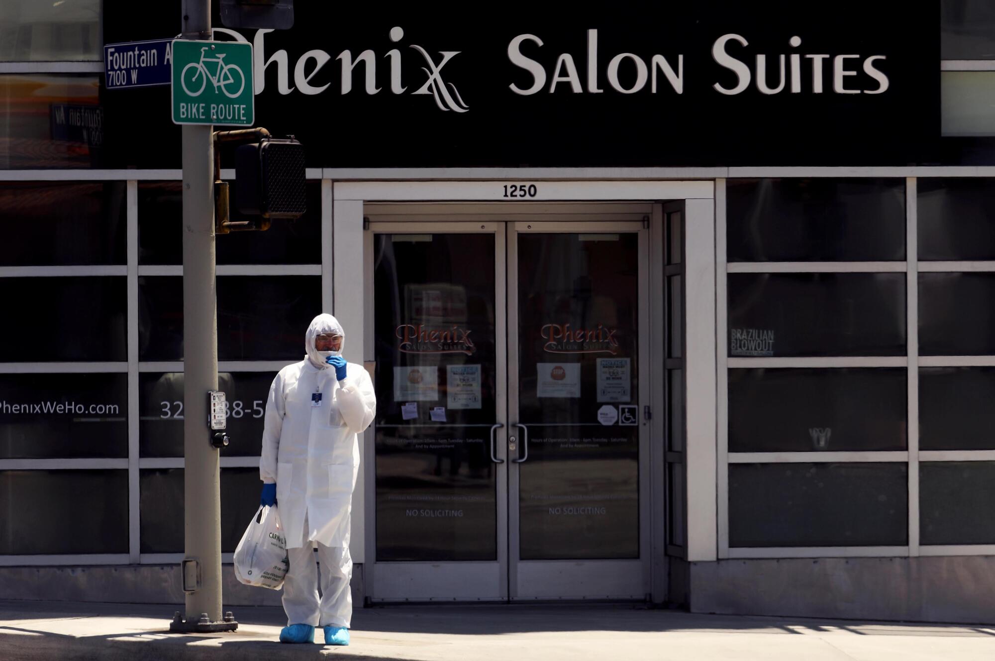 Doctor in protective suit waits to cross Fountain Avenue in Los Angeles.