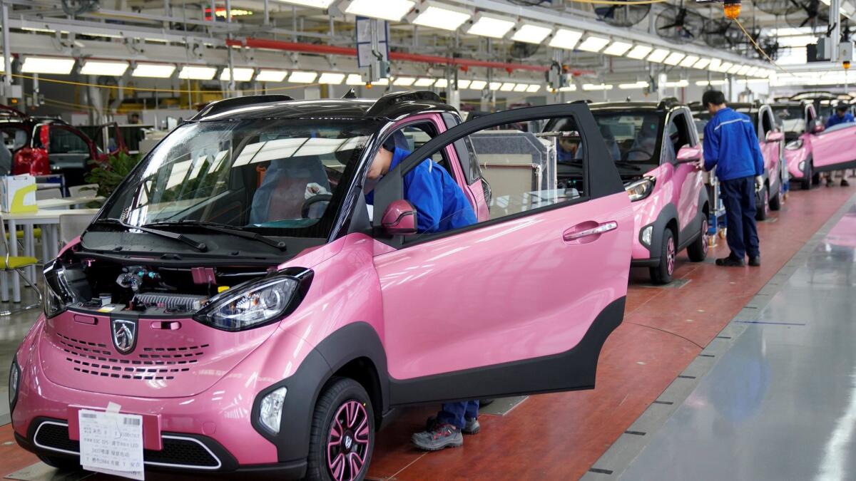 Workers in China inspect Baojun E100 all-electric battery cars at a plant operated by General Motors and its local joint-venture partners in the city of Liuzhou..