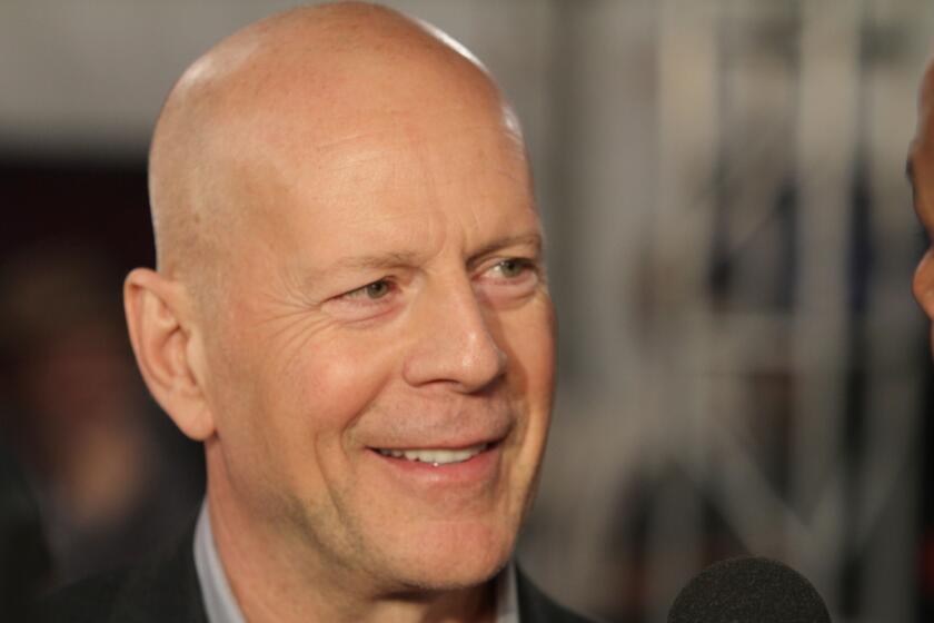 Bruce Willis smiles while looking to his left.