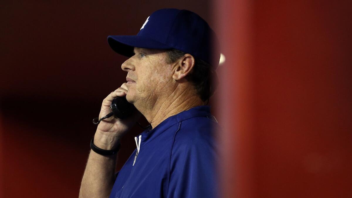 Dodgers pitching coach Rick Honeycutt on the phone in the dugout during a game.