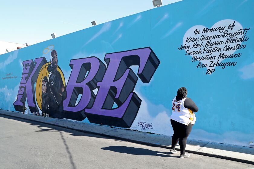 A fan reads the names of Los Angeles Lakers legend Kobe Bryant, his daughter Gianna and the seven other victims that died in a helicopter crash last year on mural painted on the side of El Toro Bravo market in Costa Mesa on Tuesday. Tuesday, January 26, 2021 marks the one-year anniversary of the their deaths.