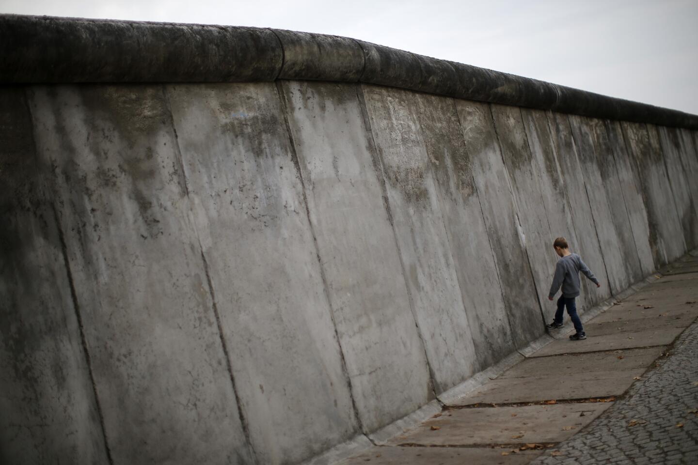 A boy kicks against a concrete segment of the Berlin Wall at the Bernauer Strasse in 2014.