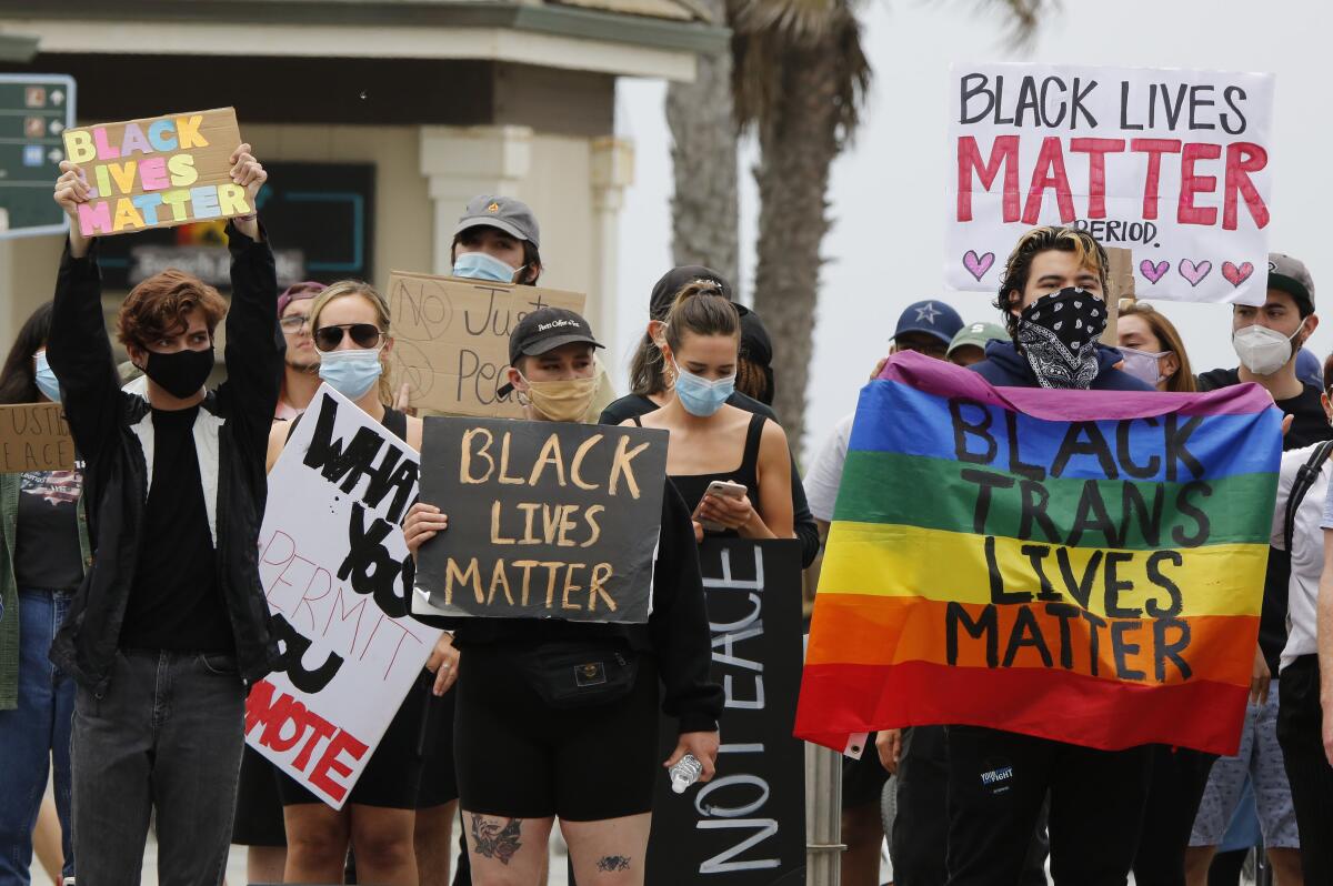 Protesters hold signs during a Black Lives Matter rally at Pier Plaza in Huntington Beach on Saturday.