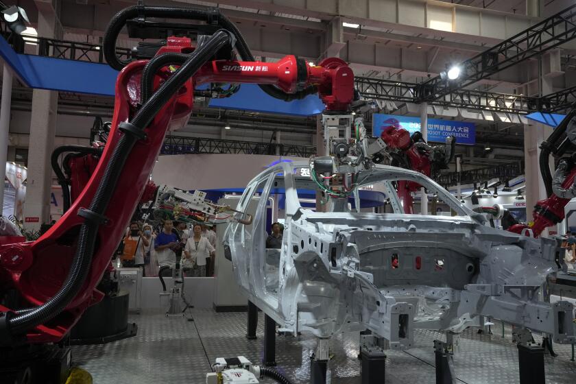 FILE - Visitors look at the robotic arms assembly a vehicle frame during the annual World Robot Conference at the Etrong International Exhibition and Convention Center in the outskirt of Beijing, on Aug. 17, 2023. China's factory activity in September recorded its first expansion in six month, an official survey said Saturday, Sept. 30, 2023, providing another sign that the world's second-largest economy is gradually improving following its post-pandemic malaise. (AP Photo/Andy Wong, File)