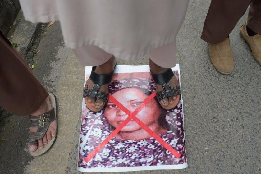 (FILES) In this file photo taken on November 2, 2018 a Pakistani supporter of the Ahle Sunnat Wal Jamaat (ASWJ), a hardline religious party, stands on an image of Christian woman Asia Bibi as they march during a protest rally following the Supreme Court's decision to acquit Bibi of blasphemy, in Islamabad. - Asia Bibi, the Christian woman at the centre of a decade-long blasphemy row, has left Pakistan, unconfirmed reports in local media said May 8, 2019, months after her death sentence was overturned by the country's top court. (Photo by AAMIR QURESHI / AFP)AAMIR QURESHI/AFP/Getty Images ** OUTS - ELSENT, FPG, CM - OUTS * NM, PH, VA if sourced by CT, LA or MoD **
