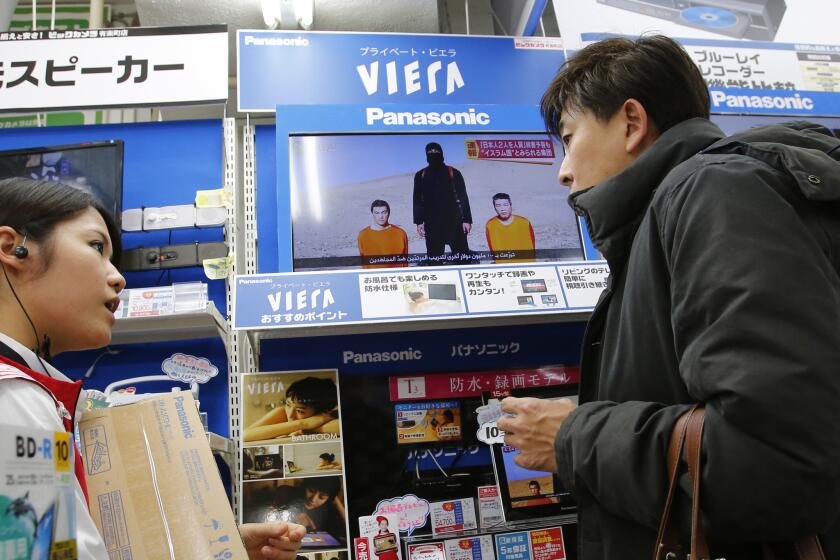 Japanese hostages held by Islamic State militants appear on a television screen in an electronics store in Tokyo on Jan. 20.