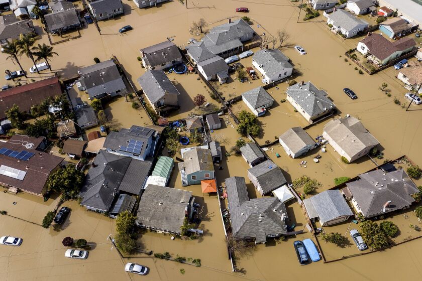 Floodwaters surround homes and vehicles in the community of Pajaro in Monterey County, Calif., on Monday, March 13, 2023. (AP Photo/Noah Berger)