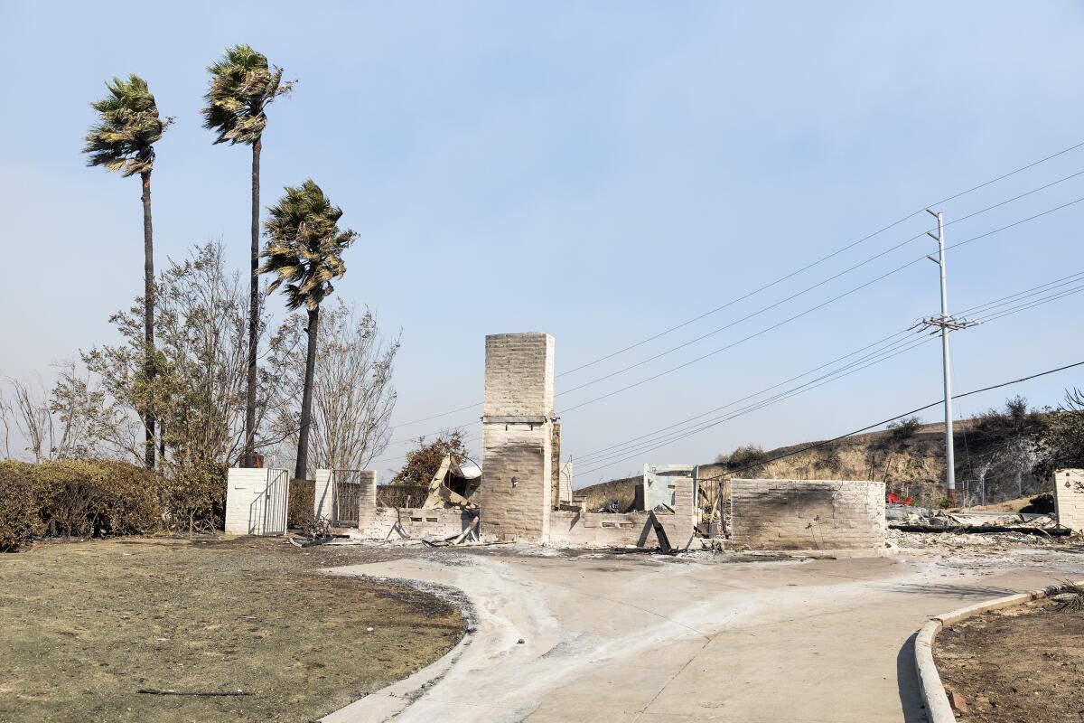 A burned house with a few walls and a fireplace standing.